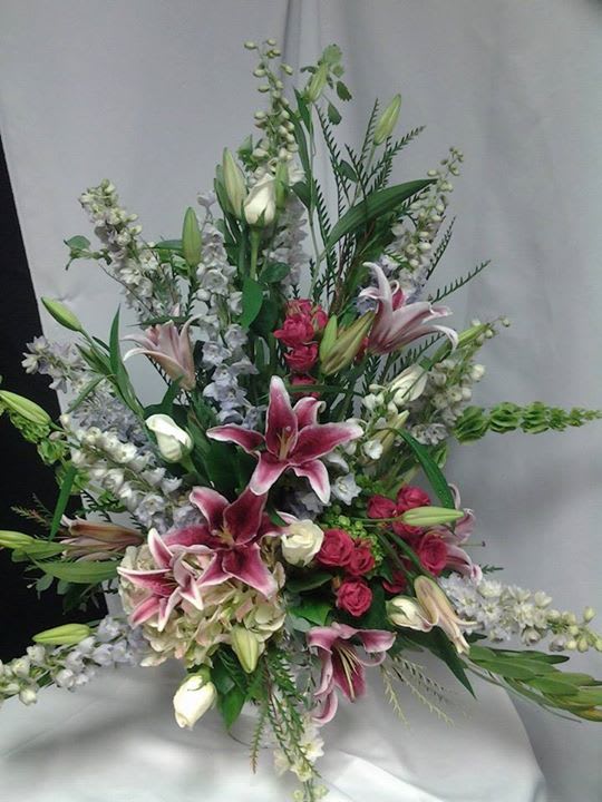 pastel urned arrangement - A spring pastel mixture of flowers such as star gazer lilies, roses, bells of Ireland in a urn. 