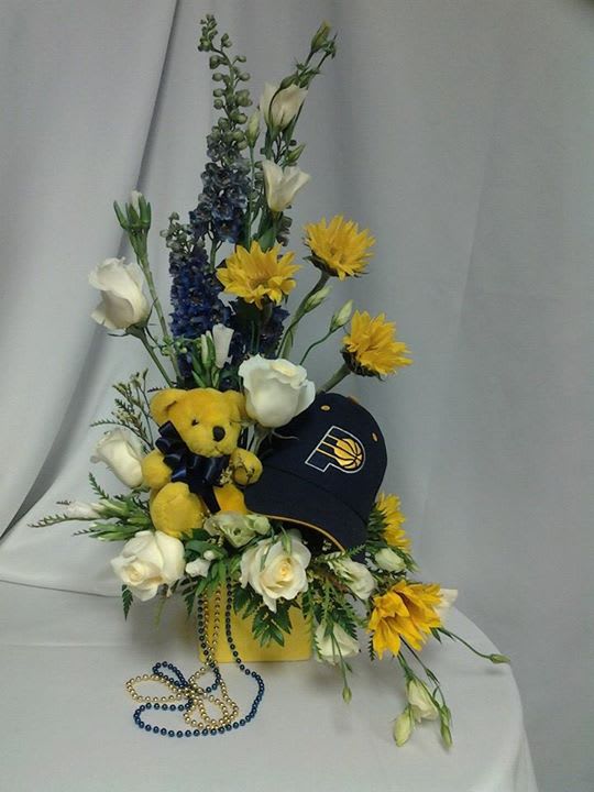Pacer Fan's arrangement - Blue &amp; yellow flowers with a baseball cap and bear to appeal to the any Pacer's fan. Looking for a fan pleaser floral arrangement? Contact us to make that special fan favorite arrangement for your sports fan.