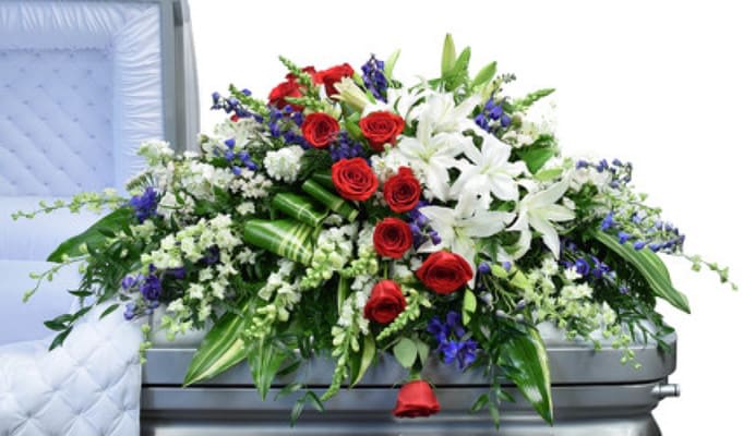 Red, White &amp; Blue Casket Spray - Beautiful White lilies, Red Roses and blue Delphinium with lush mixed greenery.