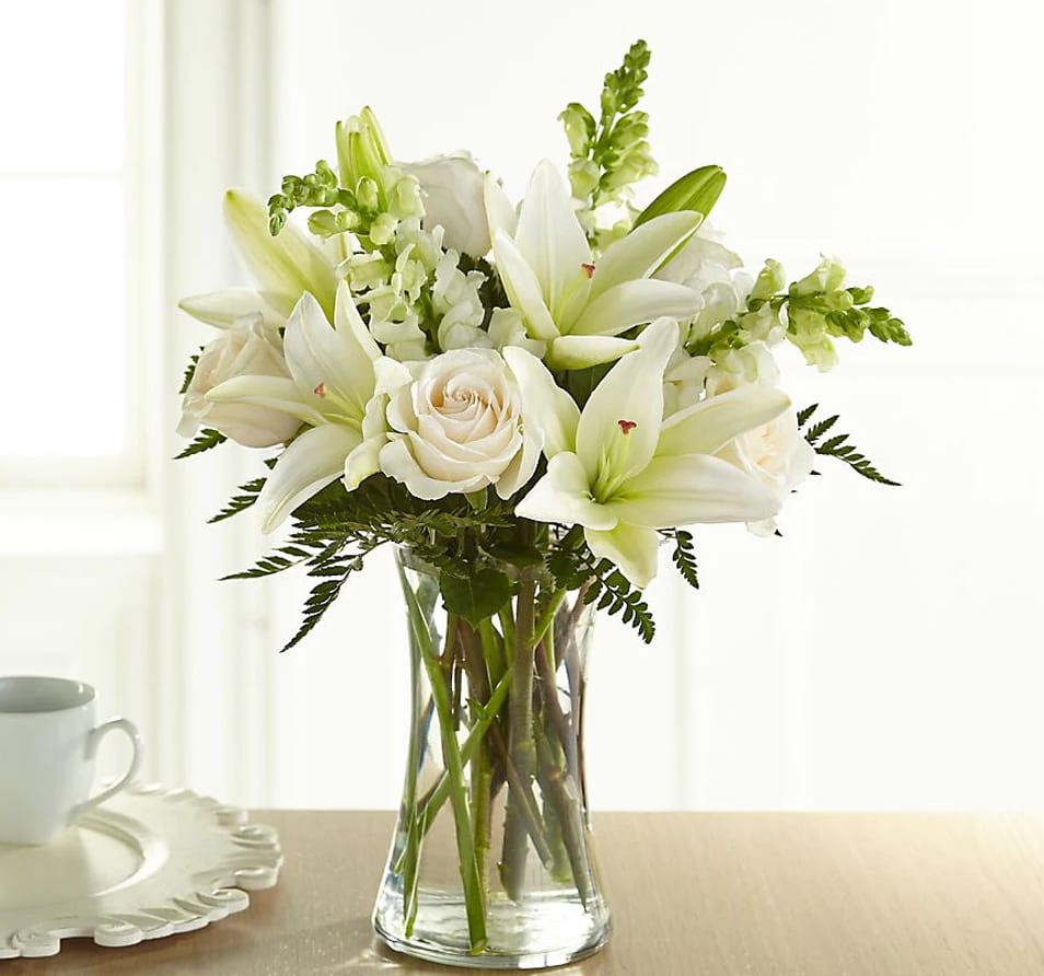 The Eternal Friendship Bouquet - An exuberance of bright and beautiful white blossoms provides an exquisite way to deliver your expressions of sympathy and comfort. This life affirming tribute combines white roses snapdragons and Asiatic lilies accented by lush greens arranged in a clear glass gathering vase. An excellent choice for a wake funeral service or for sending your condolences to the home of grieving family or friends.