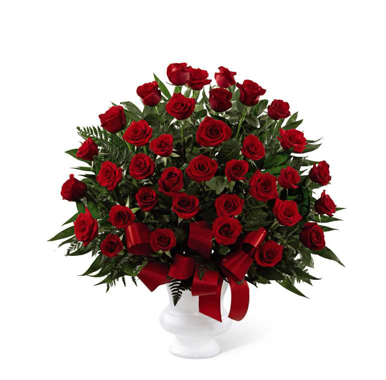 Soul's Splendor Arrangement - The FTD Soul's Splendor Arrangement is a rich display of the love shared throughout the life of the deceased. Brilliant red roses are elegantly displayed in a white designer plastic urn and accented with lush greens and red satin ribbon to create a beautiful tribute to honor your special relationship.  Bouquet is a one-sided fan shaped floral arrangement, accented with greens in the back, and set in a plastic urn container. 