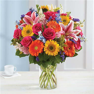 Garden Pathway™ Garden Pathway™ - Our Garden Pathway bouquet will delight with its fresh-from-the meadow design. Hand-gathered with vibrant, fragrant blooms and lush greenery for a rich contrast of color, it’s a summertime standout that deserves to be put on display. All-around arrangement with sunflowers, hot pink roses, pink Stargazer lilies and larkspur, blue delphinium, orange Gerbera daisies and purple statice; accented with assorted greenery Artistically designed in a clear glass cylinder vase; measures 8"H Large arrangement measures approximately 27"H x 25"L Medium arrangement measures approximately 25"H x 24"L Small arrangement measures approximately 24"H x 23"L Our florists hand-design each arrangement, so colors, varieties and container may vary due to local availability Lilies may arrive in bud form and will open to full beauty in 2-3 days Sunflowers may arrive with light or dark centers