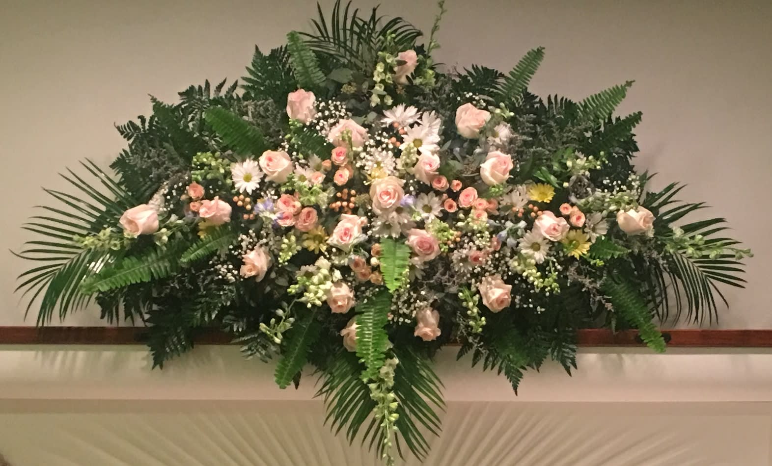 Casket Spray of Feminine, Soft Blush Colors Casket Spray of Feminine, Soft Blush Colors - Quiet expression of a life well lived. Shown in soft pink, peach and white garden flowers including Roses, Daisies, Larkspur, Hypericum and mixed greens.