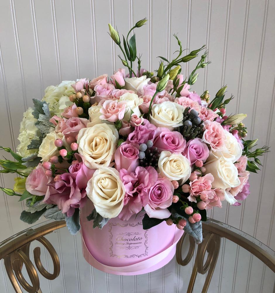 Gracie - Roses, Stock, Licentious and Lush White Hydrangeas. Gracie - Roses, Stock, Licentious and Lush White Hydrangeas. - This Chocolato arrangement is made with pink and yellow roses, stock, licentious, greenery and lush white hydrangeas. The arrangement comes in a pink round box. Please see care instructions for further assistance on taking care of your Chocolato Boxed Flowers. All prices are subject to change due to season and availability of fresh flowers. The arrangement seen is what will be made unless any substitution may need to be made based on season and availability of flowers.