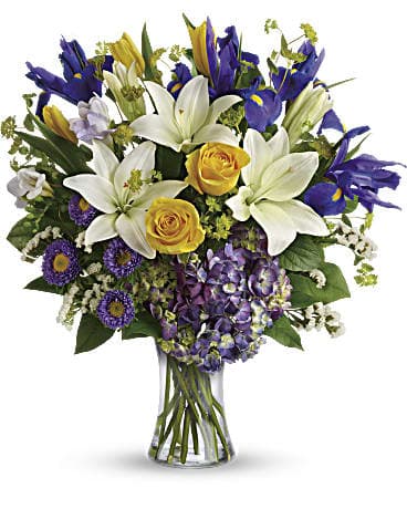 Teleflora's Floral Spring Iris Bouquet - This luxurious mix of hydrangea roses tulips lilies and irises brings the glory of a fresh spring sky to any occasion! What a majestic mix of blues yellows and whites gracefully gathered in a classic glass vase.