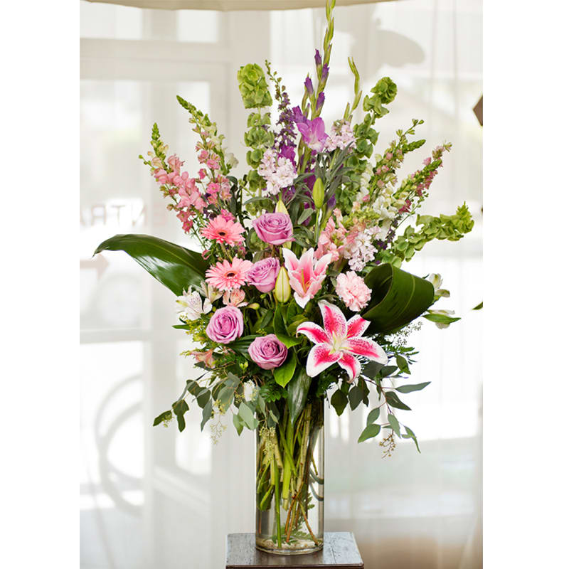 Bella Petals ***** - Item Code: 113-VF approx. 3 1/2 ' h x 14&quot;w   The stunning, Bella Petals bouquet really makes a statement!  This gorgeous creation is made up of beautiful stargazer lilies, lavender roses, purple gladiolas, pink larkspur, snapdragons, white alstoemeria, stock, pink gerbera daisies, and green bells of Ireland.    