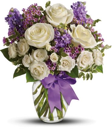 Enchanted Cottage -   As enchanting as coming across a hidden cottage in the countryside! Lush white roses and purple stock mix with delicate lavender waxflower and green pitta negra for an elegant English garden look. The decorative bouquet is finished with a pretty satin ribbon.  White roses meet lavender stock and waxflower in this lush, elegant arrangement. 