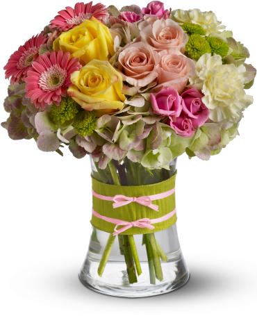 Fashionista Blooms -   Flowers are always in fashion! Especially this chic mix of pinks, greens and yellows, arranged in a style evoking the English hand-tied bouquet. It's a stylish surprise for any lucky lady.  Mini pink gerberas, lush green hydrangea, yellow and pink roses, yellow carnations and green button mums are arranged in a clear concave vase that's trimmed with a chartreuse taffeta ribbon and pink raffia. 