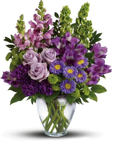 Lavender Charm Bouquet -   Charmed, I'm sure! Win their hearts with this winsome bouquet of luxurious lavender blooms and delightful bells of Ireland, hand-delivered in a graceful glass vase.  This lovely bouquet features lavender roses, purple alstroemeria, purple carnations, lavender matsumoto asters, green button spray chrysanthemums, lavender snapdragons, bells of Ireland, huckleberry and lemon leaf. 