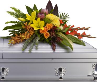 Island Memories Casket Spray -  Tropical flowers evoke tropical breezes in this modern style casket spray. Deep red ti leaves and aspidistra leaves frame fresh and fragrant yellow lilies and chrysanthemums, along with orange orchids, roses and red gladioli. 