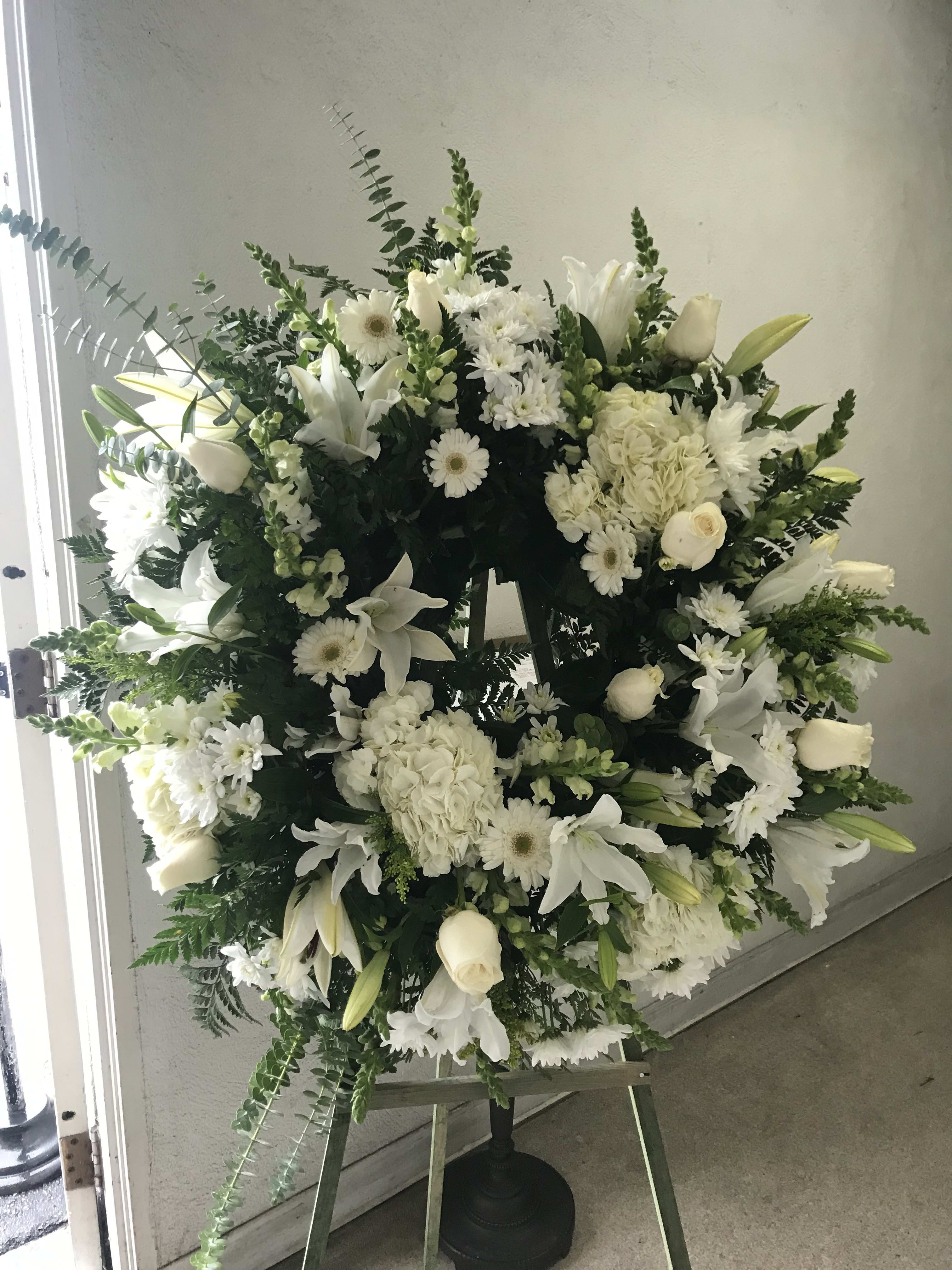 ON SALE- WAS $240- OUR HEARTS GO OUT TO YOU AND YOUR FAMILY WREATH ON SALE- WAS $240- OUR HEARTS GO OUT TO YOU AND YOUR FAMILY WREATH - A BEAUTIFUL ARRAY OF WHITE FLOWERS, SUCH AS ROSES, LILYS AND MORE, ACCENTED WITH EUCALYPTUS. SITS ON A 5 FOOT EASEL