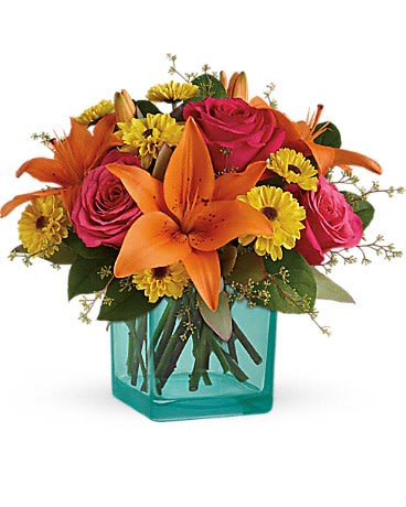 Teleflora's Fiesta Bouquet - A party of petals! Celebrate any occasion with this fun-filled bouquet that brightens their day with fuchsia roses and orange liles presented in a beautifully contrasting turquiose cube vase.