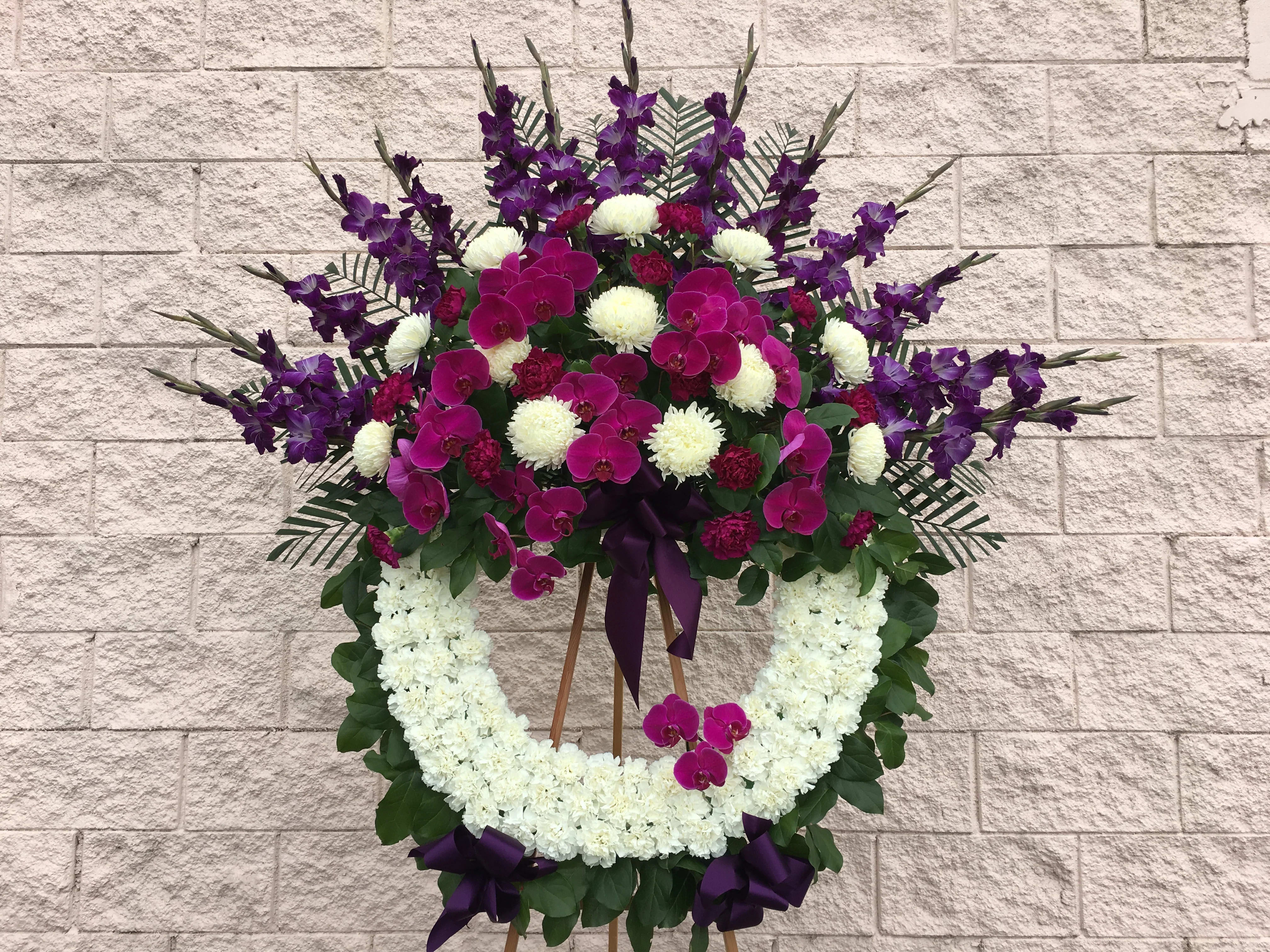 Phalaenopsis Japanese Wreath - The traditional wreath with a white carnation ring, white china mum, dark purple gladiolas, purple carnations and purple phalaenopsis orchids. 