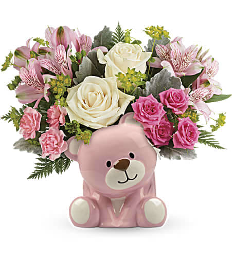 Teleflora's Precious Pink Bear Bouquet - Honor a precious arrival with gorgeous cream roses and delicate pink blooms, beautifully bundled in a sweet ceramic teddy bear keepsake. This precious bouquet includes crème roses, pink spray roses, pink alstroemeria, pink miniature carnations, bupleurum, dusty miller, and leatherleaf fern. Delivered in a pink Bundle of Love Bear. Approximately 12 1/2&quot; W x 11&quot; H 