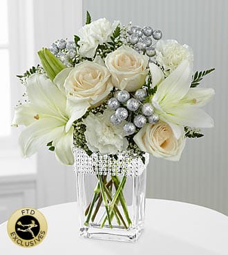 The FTD® Intriguing Grace™ Bouquet - BL1S  The FTD® Intriguing Grace™ Bouquet speaks to a pure beauty and alluring style that can only be defined through these exquisite blooms. Drenched in the modern sophistication of white, these roses, Asiatic Lilies, carnations and Million Star Gypsophila are brought together and offset by lush greens to create an impressive flower arrangement. Presented in clear glass vase with silver beading lined at the top and accented with silver glitter ball pics for an added touch of lovely, this mixed flower bouquet will make an excellent thank you, anniversary, or engagement gift.