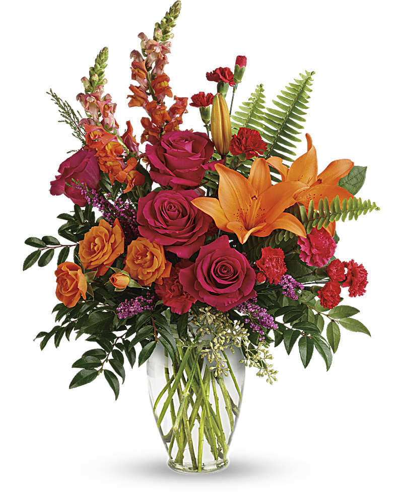 Punch Of Color Bouquet - The bright stuff for punching up anyone&#039;s mood! Bring happiness to any day with this bold sunset-inspired blend of hot pink roses and orange lilies in a classic glass vase! Hot pink roses orange spray roses orange asiatic lilies hot pink carnations red miniature carnations orange snapdragons and pink heather are accented with sword fern huckleberry seeded eucalyptus and lemon leaf. Delivered in a clear glass vase.
