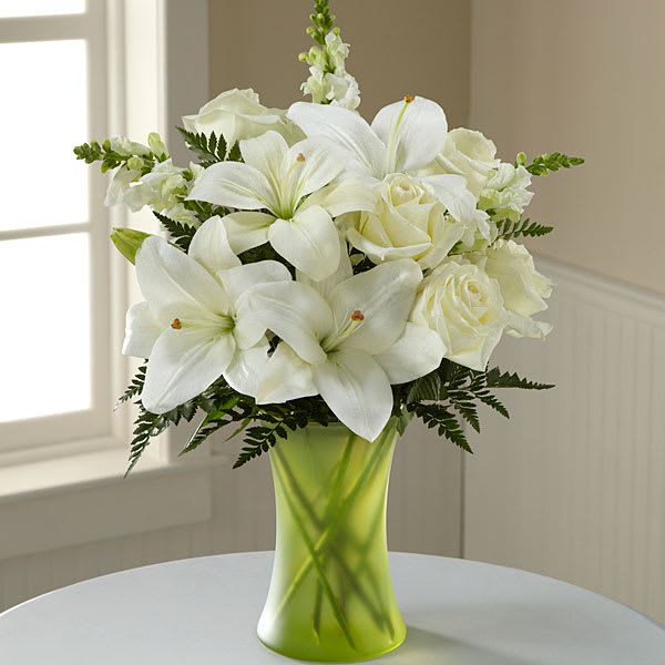 The FTD Eternal Friendship Bouquet - An exuberance of bright and beautiful white blossoms provides an exquisite way to deliver your expressions of sympathy and comfort. This life affirming tribute combines white roses snapdragons and Asiatic lilies accented by lush greens arranged in a matte green glass gathering vase. An excellent choice for a wake funeral service or for sending your condolences to the home of grieving family or friends.
