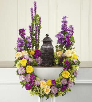 The FTD Garden of Grace Arrangement The FTD Garden of Grace Arrangement - This masterpiece of floral sympathy creates a beautiful and reverential tabletop setting for an urn holding the cremated remains of your loved one. Handcrafted by a local FTD artisan florist this stunning and original creation is perfect for formal visitation or memorial services. Constructed on a modified wreath frame it combines cream and yellow roses fuchsia Dianthus purple Liatris and stock lavender cushion pompons green trachelium and hydrangea all accented with lush greenery including ivy vines.