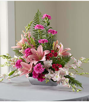 The FTD® Uplifting Moments™ Arrangement - This beautiful, blushing tribute to a life well-lived is an excellent choice for expressing your sympathy in a color palette that reflects the taste of the deceased. Handcrafted in gorgeous shades of pink from soft-to-saturated by a local FTD artisan florist this lovely arrangement includes roses, carnations, Dendrobium orchids, snapdragons and Asiatic lilies accented with graceful greens in a rectangular bowl of brushed silver-tone metallic plastic. It brings a welcome, refreshing note to the solemnity of wakes and funeral services and is bound to be long remembered and appreciated.  Your purchase includes a complimentary personalized gift message.