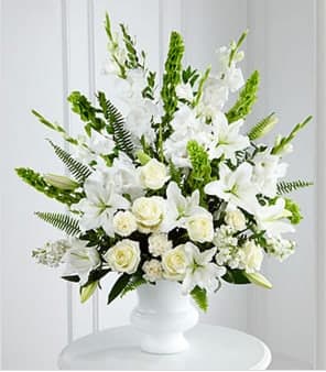 The FTD® Morning Stars™ Arrangement - The FTD® Morning Stars™ Arrangment is a brilliant expression of peace and soft serenity. White roses, carnations, gladiolus, stock and Oriental lilies are accented with the bright green stems of Bells of Ireland and a gorgeous assortment of lush greens, while seated in a designer plastic urn to create a beautiful way to honor the life of the deceased. GOOD arrangement includes 31 stems. Approximately 36&quot;H x 30&quot;W. BETTER arrangement includes 43 stems. Approximately 40&quot;H x 32&quot;W. BEST arrangement includes 55 stems. Approximately 45&quot;H x 36&quot;W. Your purchase includes a complimentary personalized gift message.