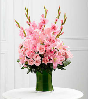 The FTD® Lovely Tribute™ Bouquet - The FTD® Lovely Tribute™ Bouquet is a warm and blushing display of peace and beauty, set to honor the deceased and bring comfort to family and friends. Pink gladiolus, pale pink roses, pink spray roses, pink Asiatic liles and an assortment of lush greens create a sophisticated arrangement seated in a clear glass gathering vase, symbolizing your heartfelt love and sympathy. GOOD bouquet includes 18 stems. Approximately 27&quot;H x 17&quot;W. BETTER bouquet includes 26 stems. Approximately 28&quot;H x 19&quot;W. BEST bouquet includes 33 stems. Approximately 30&quot;H x 22&quot;W. Your purchase includes a complimentary personalized gift message.