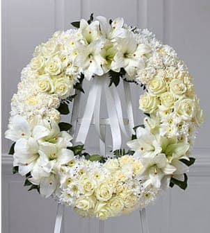 The FTD® Wreath of Remembrance™ - The traditional funeral wreath, beautifully representing the eternal circle of life, is updated for a new era and is beautifully refreshed without losing any of its poignant meaning. This impressive wreath, handcrafted by an FTD artisan florist to deliver your condolences, is constructed of white roses, carnations and Asiatic lilies complemented by lush greens and ribbon and trim. It makes a superb, time-honored addition when displayed on a wooden easel for a wake or funeral service, graveside at a burial, to decorate a headstone or to set adrift for burials at sea.  Your purchase includes a complimentary personalized gift message.