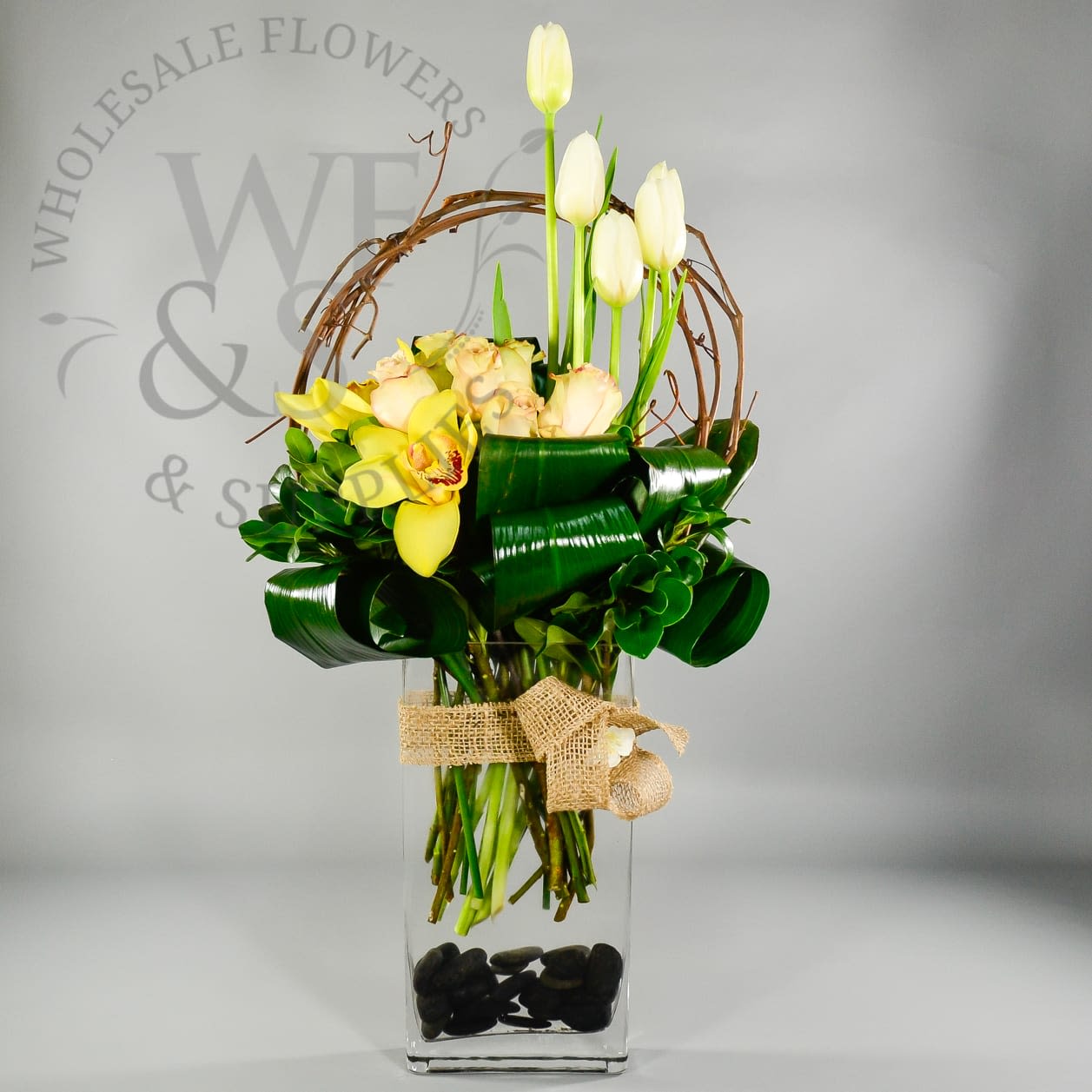 RAIN FOREST FRESH - roses tulips and cymbidium orchids on a bed of greens inside a rectangular clear vase