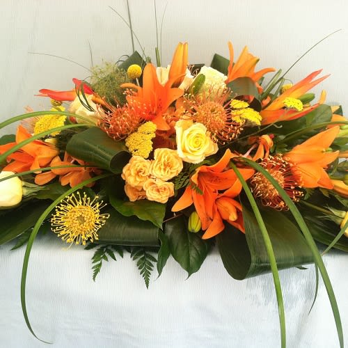 Orange Masculine open Casket Spray Orange Masculine open Casket Spray - This open casket spray contains several exotic flowers such as Pin Cushion protea, min- haleconias , orchids and lilies. Please provide 2 days notice.