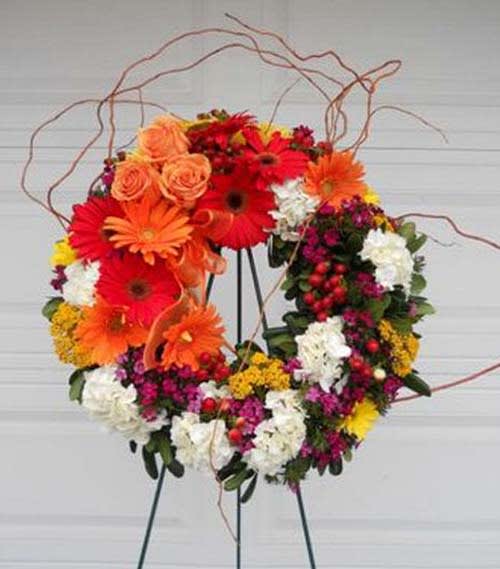 Gerber Daisy 20" Wreath Gerber Daisy 20" Wreath - This woodsy masculine wreath boasts 10 bright orange Gerber daisies, roses, hydrangea, yarrow and berries. Generous amounts of bent curly willow expand the overall look and size.
