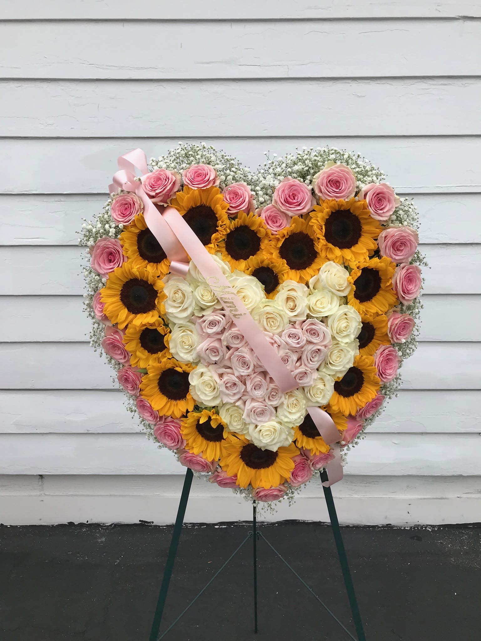 Heart Shaped Easel Spray - A grand heart-shaped easel spray for the memorial of a loved one. This beautiful expression of sympathy is created with a lovely combination of sunflowers and roses.