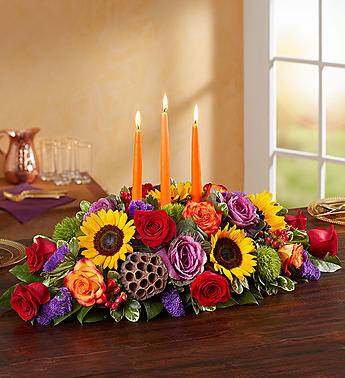 Garden of Grandeur for Fall Centerpiece - We’ve designed one of our most impressive fall bouquets into a luxurious centerpiece. Radiant roses and sunflowers are hand-gathered with a mix of brightly colored blooms and unique accents, creating a truly unique gift.