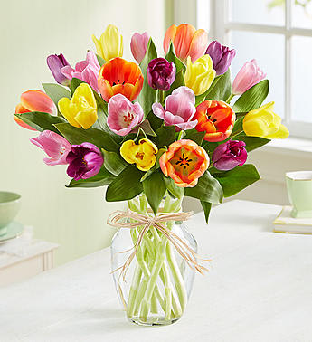 Timeless Tulips - These timeless spring blooms are bursting with beautiful color, hand-arranged inside a clear glass vase tied with a charming raffia bow. Send a bunch today to make somebody smile bright.