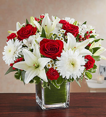 Healing Tears™ Red &amp; White - The color most related the heart, let red serve as a reminder that they will live forever in the hearts of loved ones. Our sympathy arrangement of timeless red roses, carnations, and white lilies, expertly gathered together in a clear glass cube lined with a Ti leaf ribbon, it is an exquisite gesture of comfort and healing.
