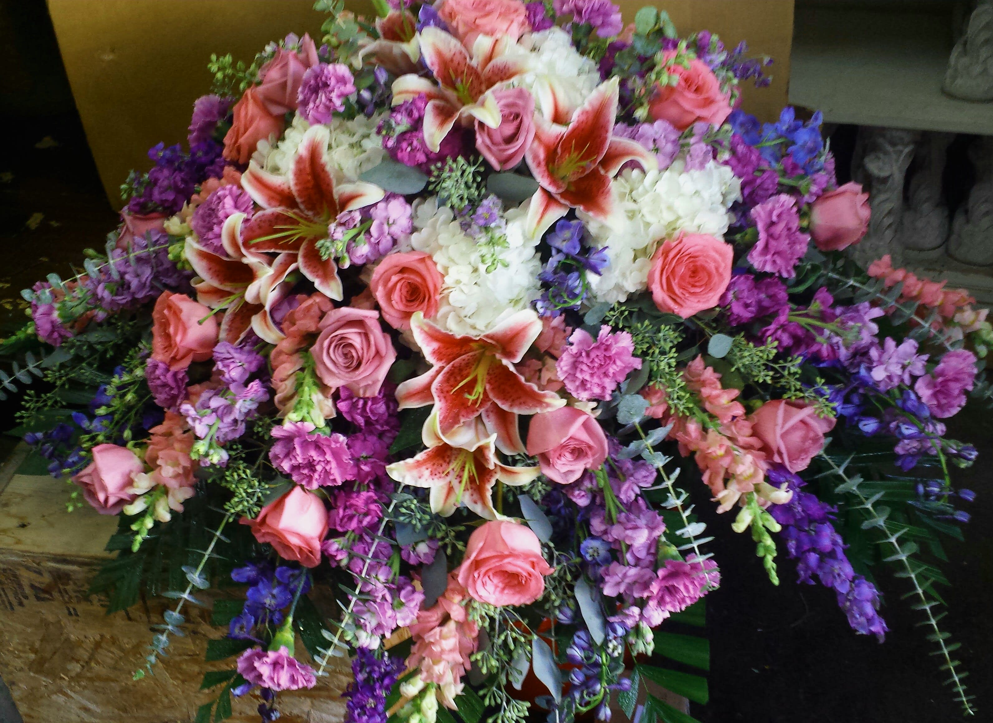 Eckert Florist's Stargazer Casket Spray - This casket spray features stargazer lilies, hydrangeas and a mix of our finest blooms in pinks, lavenders and purples.
