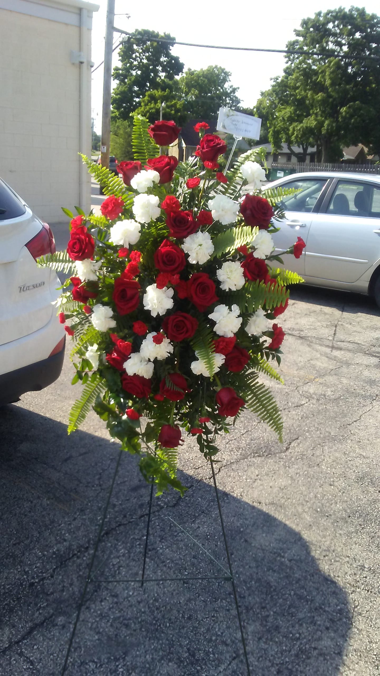 Standin spray red - Red and white carnations,  roses, and greenery 