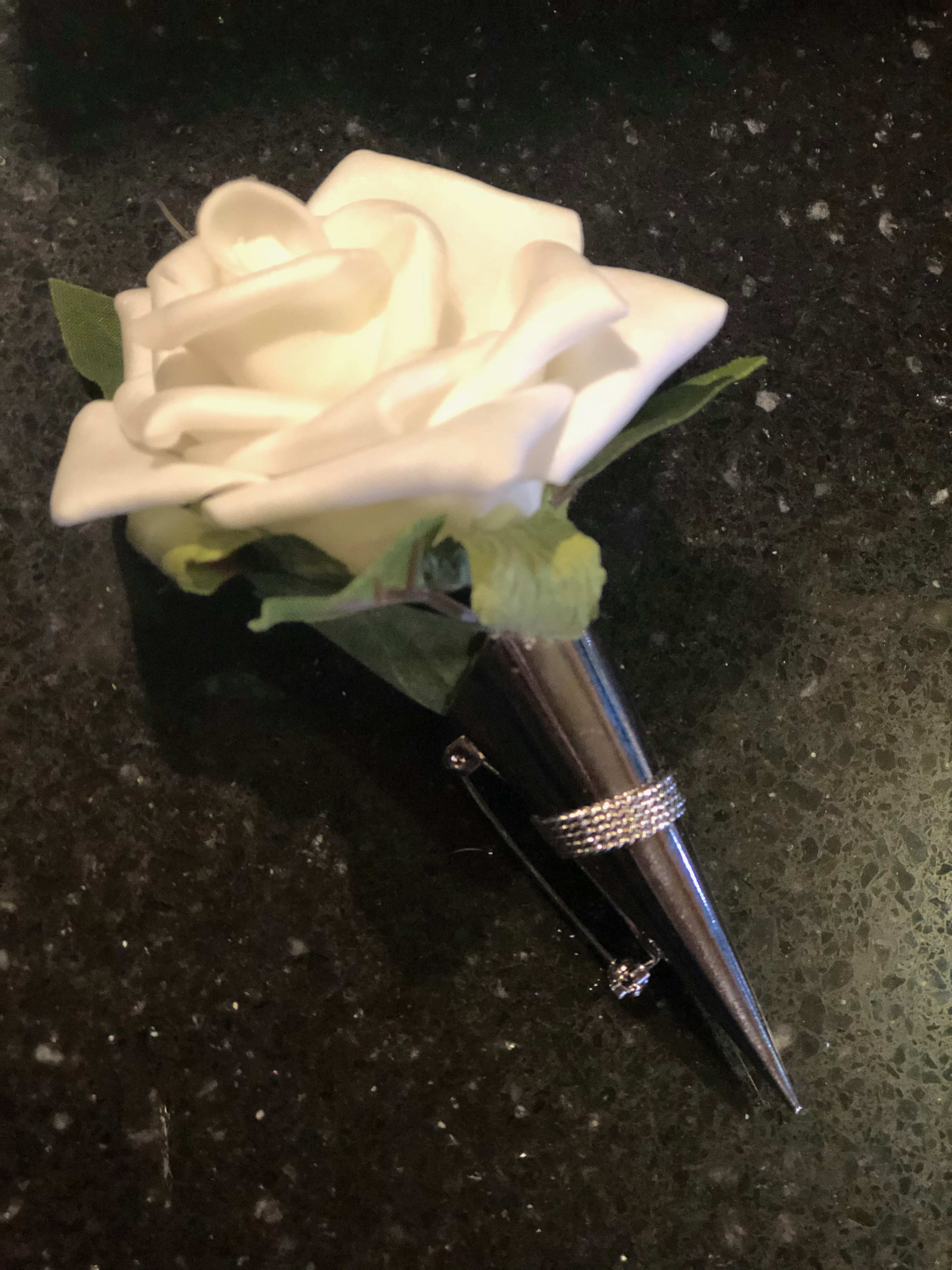 Forever Yours - A beautiful boutonnière with one silk white spray rose nestled into a silver lapel pin vase with silk greenery accents. Can be used over and over. Sure to become a keepsake. 