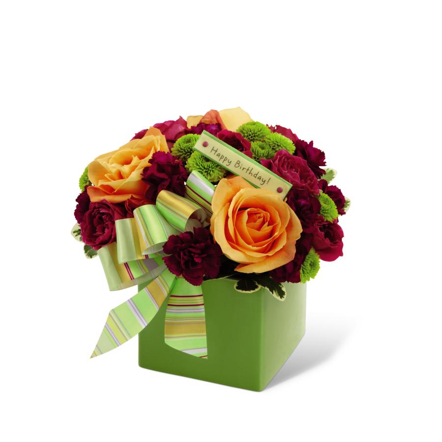 FTD Birthday Bouquet - The FTD Birthday Bouquet is an expression of warm sentiments and   fantastic fortune for the year to come! Orange roses, fuchsia spray   roses, plum miniature carnations and green button poms are beautifully   arranged in a designer green ceramic block vase and accented with a   decorative ribbon to create the perfect way to wish them well on their   big day.  