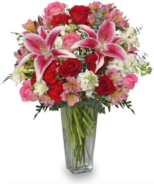 CF2206 - Eternally Yours  Express your devotion with this floral masterpiece featuring a lush assortment of Stargazer Lilies, Red Roses, Pink Roses, Red Carnations, Pink Alstroemeria, White Stock, White Freesia, White Waxflowers, and foliage artfully arranged in an elegant glass vase.   Copyrighted content provided by FlowerShopNetwork.com Proud Member of Flower Shop Network