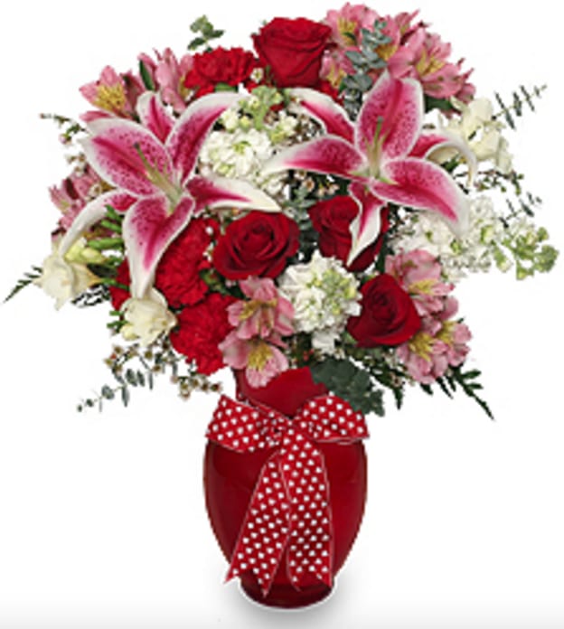 F201 - That's Amore! Express your affection perfectly with this floral masterpiece featuring a lush assortment of Stargazer Lilies, Red Roses, Red Carnations, Pink Alstroemeria, White Stock, White Freesia, White Waxflowers, and foliage artfully arranged in an elegant red vase adorned with red and white ribbon.   Copyrighted content provided by FlowerShopNetwork.com Proud Member of Flower Shop Network