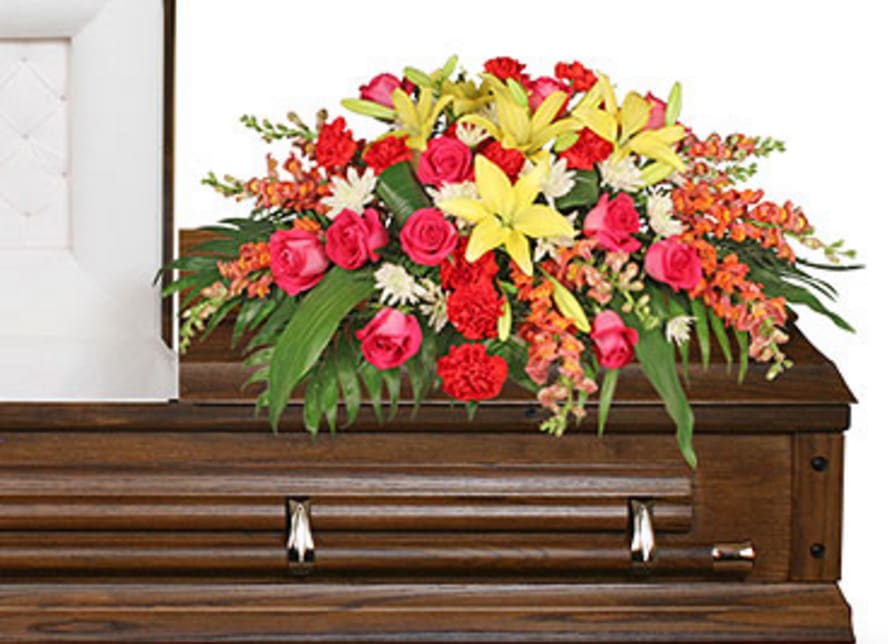 CF2105 - In Loving Memory In loving memory features a lush assortment of Aspidistra Leaves, Jade, Leather Leaf, Peach Snapdragons (Talisman), Yellow Lilies, Red Carnations, Hot Pink Roses, and White Cushion Poms artfully arranged in an elegant casket spray. 