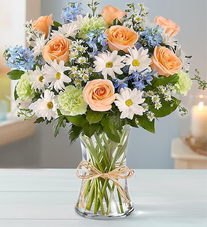 Well Wishes - Our beach-inspired bouquet captures the blissful beauty of a seaside retreat. A gathering of blooms in soothing, cool shades is hand-arranged inside a glass vase and tied with raffia for an extra touch of coastal style. 