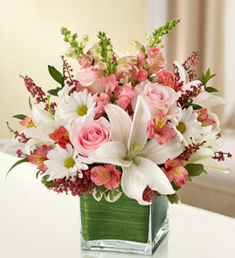 BN95390 - Healing Tears - Pink and White The elegant of our pink and white arrangement conveys your heartfelt condolences to friends and family. Gathered in a lovely cube vase by our florists, pink roses, snapdragons and heather mix with graceful white lilies and daisy poms to present a tasteful tribute.