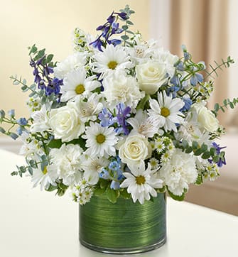 BN 95409 - Cherished Memories - Blue and White Remember a loved one during times of sorrow with a beautiful blue and white sympathy arrangement. This graceful gathering of roses, delphinium, alstroemeria, carnations and daisy poms is elegantly arranged in a stylish cylinder vase to offer a comforting expression of condolences.