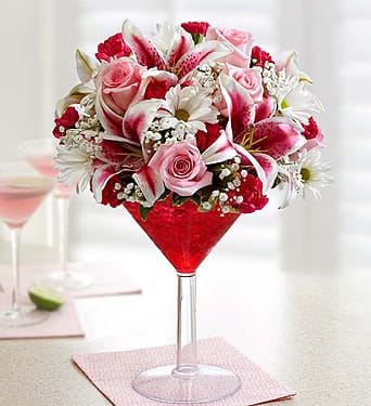 Cosmopolitan Bouquet - If they have a taste for all things modern, we’ve got just the gift for that special someone! This modern hand-arranged bouquet, from our signature floral cocktail collection, is artistically designed with pink roses, lilies and mini carnations in an oversized martini glass to help them celebrate in style! Product Code: 95264