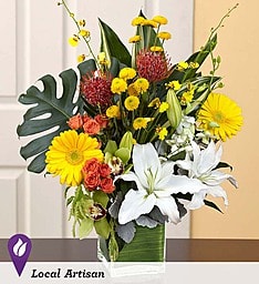 BN 99112 - Tropic Breeze Transport them to a tropical paradise with this truly original, luxurious arrangement Exotic orchids, radiant roses, graceful lilies, and bright Gerbera daisies evoke sunny splendor, while lush clusters of rare, gorgeous greens bring to mind the serenity and natural beauty of the rainforest. Personally created by your local florist, this impressive arrangement brings the beauty and warmth of a tropical breeze into their home, with unforgettable elegance and style.