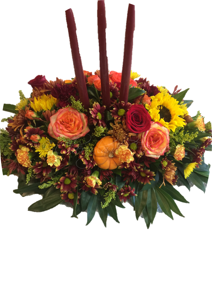 Thankful Blooms - All the splendor of Autumn is showcased in this gorgeous centerpiece of red and orange roses, red and butterscotch daisies, orange mini carnations, sunflowers, solidago, mini pumpkins, and greenery adorned with three taper candles. 