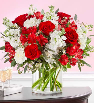 Crimson Rose Bouquet - A classic gift for the people and moments worth celebrating. Rich red and pristine white blooms are hand-gathered with lush greenery. A clear glass cylinder vase holds this beautiful surprise, which brings your deepest sentiments to light.