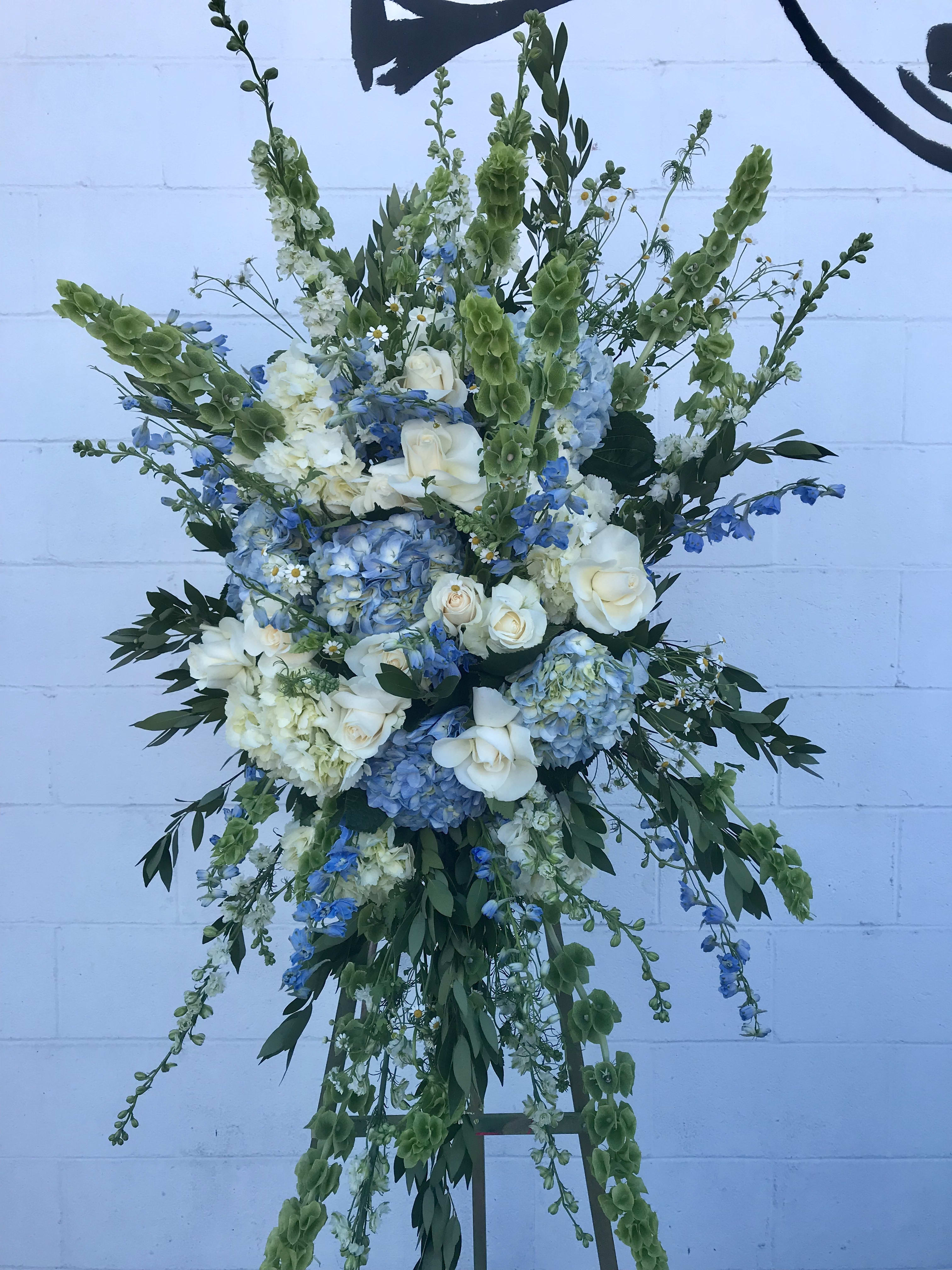 I am going to miss you!  - Large floral spray in seasonal blue and white flowers with greenery.  Stand is included with spray easel.