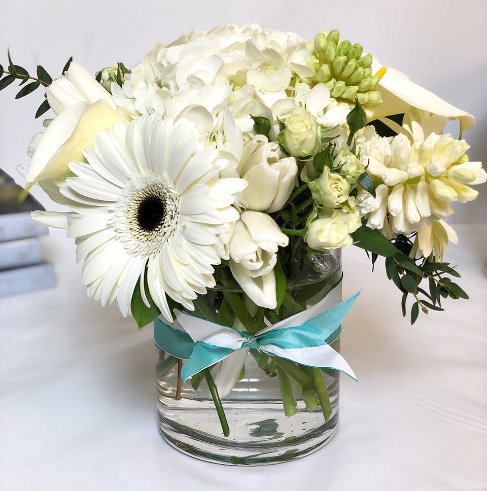 Crisp and White AD5 - The perfect arrangement for the lover of everything crisp and white -- all artfully arranged in a clear cylinder vase with a ribbon tie to complement the arrangement. . 