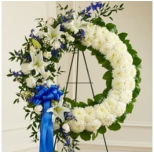 Serene Blessings Blue & White Standing Wreath Serene Blessings Blue & White Standing Wreath - With blue flowers that symbolize truth and white blooms that signify honor, this standing wreath arrangement beautifully reflects all the love and sympathy that is in your heart. Exquisitely crafted by our expert florists, it features a gathering of fresh blue delphinium, white roses, lilies, mums and more. •Arrangement measures approximately 32”H x 28”W without easel. Easel is delivered with arrangement.